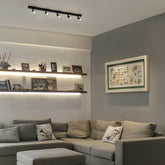 Modern living room with gray sectional sofa, wall art, and ceiling lights.